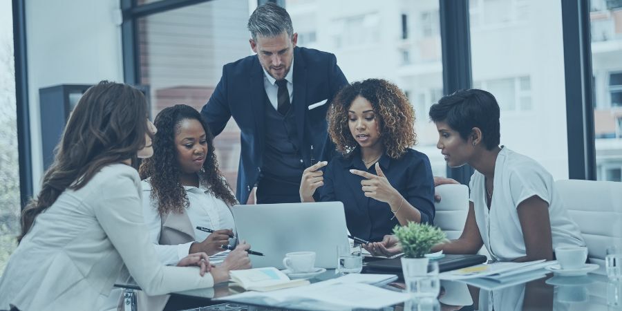 Team of business professionals having a collaborative discussion around a laptop in a modern office.