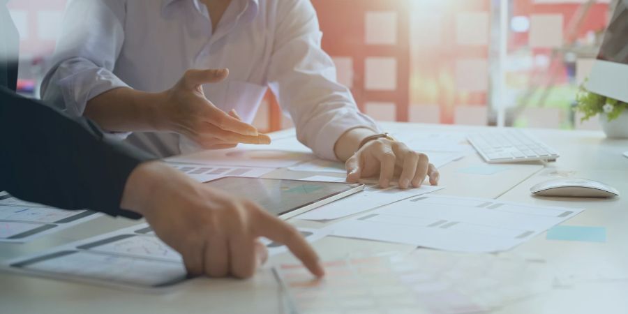 Close-up of business professionals collaborating over documents and a tablet at a desk.