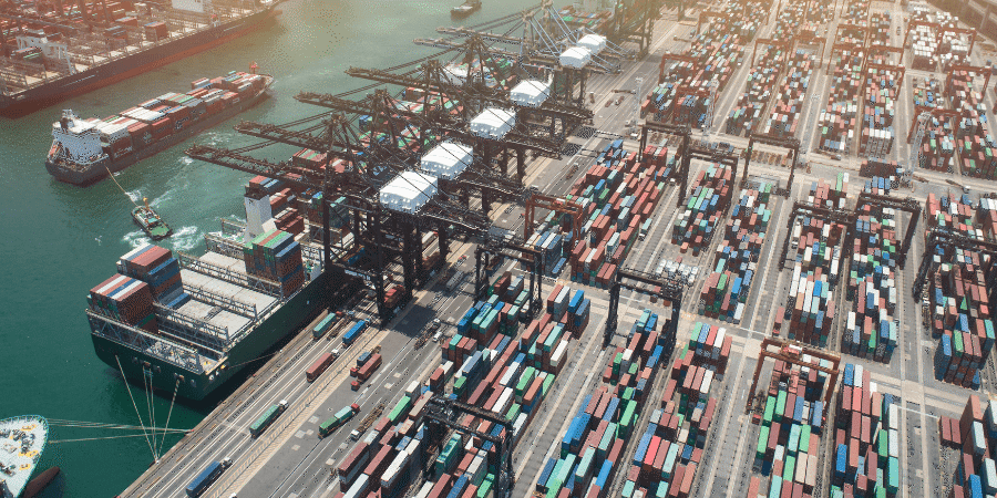 Aerial view of a busy shipping port with cranes and numerous cargo containers.